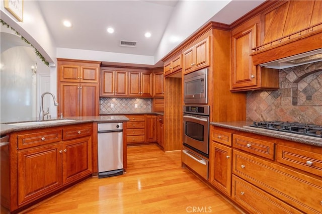 24302 Vista Ridge Dr, Valencia, CA 91355 - kitchen with appliances with stainless steel finishes, a warming drawer, brown cabinetry, light wood-style floors, and backsplash