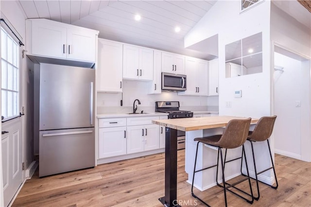 24302 Vista Ridge Dr, Valencia, CA 91355 - kitchen with stainless steel appliances, white cabinetry, light wood-type flooring, butcher block counters, and a kitchen bar