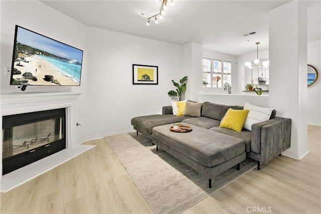 305 W Duarte Rd Unit G, Monrovia, CA 91016 - living area featuring light wood-style flooring, a chandelier, and a glass covered fireplace