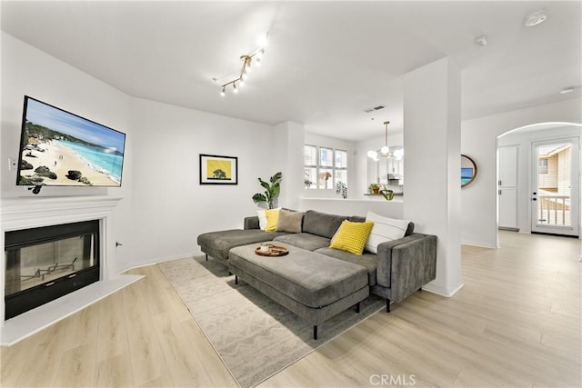 305 W Duarte Rd Unit G, Monrovia, CA 91016 - living room with arched walkways, light wood finished floors, a glass covered fireplace, and a chandelier