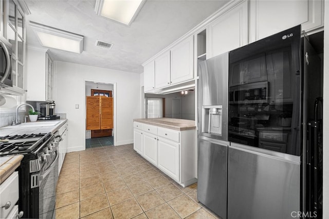 7028 E Parkcrest St, Long Beach, CA 90808 - kitchen featuring appliances with stainless steel finishes, white cabinets, light countertops, glass insert cabinets, and light tile patterned floors