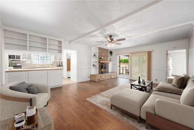 7028 E Parkcrest St, Long Beach, CA 90808 - living room featuring a ceiling fan, wood finished floors, a warm lit fireplace, beam ceiling, and built in shelves