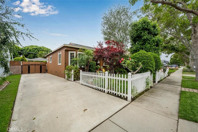 7028 E Parkcrest St, Long Beach, CA 90808 - view of front facade with a gate, a fenced front yard, concrete driveway, and stucco siding