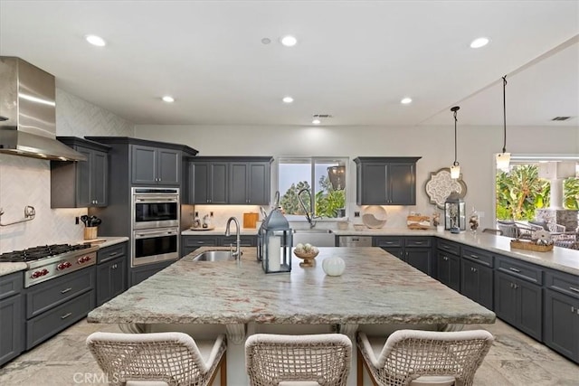 17180 Mockingbird Canyon Rd, Riverside, CA 92504 - kitchen with appliances with stainless steel finishes, wall chimney exhaust hood, a kitchen bar, recessed lighting, and light stone countertops