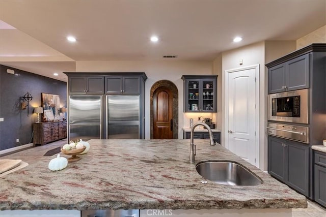 17180 Mockingbird Canyon Rd, Riverside, CA 92504 - kitchen with appliances with stainless steel finishes, a warming drawer, light stone counters, recessed lighting, and arched walkways