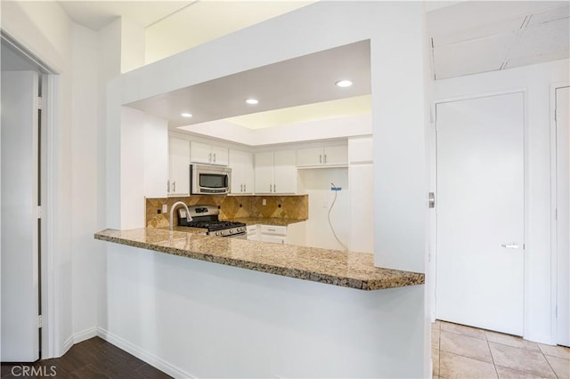 5151 Balboa Blvd Unit 104, Encino, CA 91316 - kitchen featuring stainless steel appliances, light stone counters, decorative backsplash, white cabinets, and recessed lighting