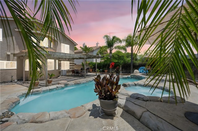 566 Bruin Dr, Riverside, CA 92507 - pool at dusk with a patio, a pergola, a fenced backyard, and a pool with connected hot tub