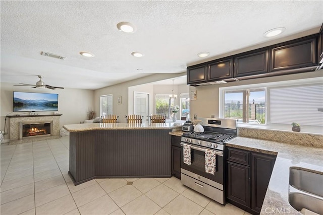 566 Bruin Dr, Riverside, CA 92507 - kitchen featuring stainless steel range with gas cooktop, ceiling fan, healthy amount of natural light, a textured ceiling, and a glass covered fireplace