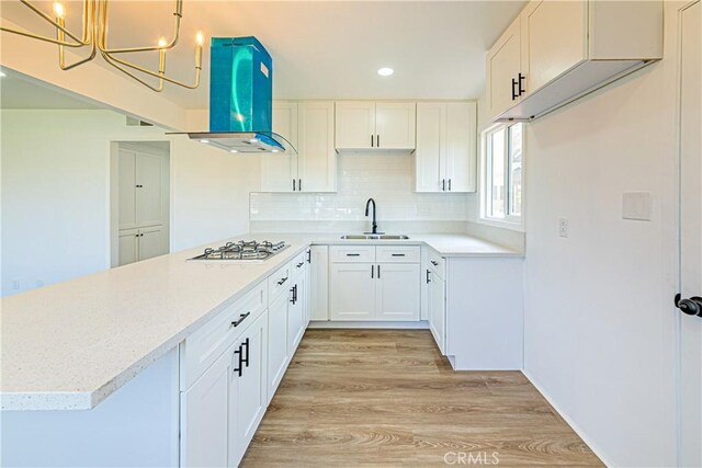 1510 W 147th St, Gardena, CA 90247 - kitchen with a peninsula, stainless steel gas cooktop, light wood-style floors, a chandelier, and decorative backsplash