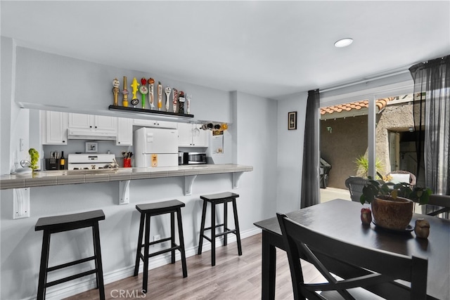 22524 Paseo Terraza, Saugus, CA 91350 - kitchen with freestanding refrigerator, range, tile counters, white cabinets, and a breakfast bar