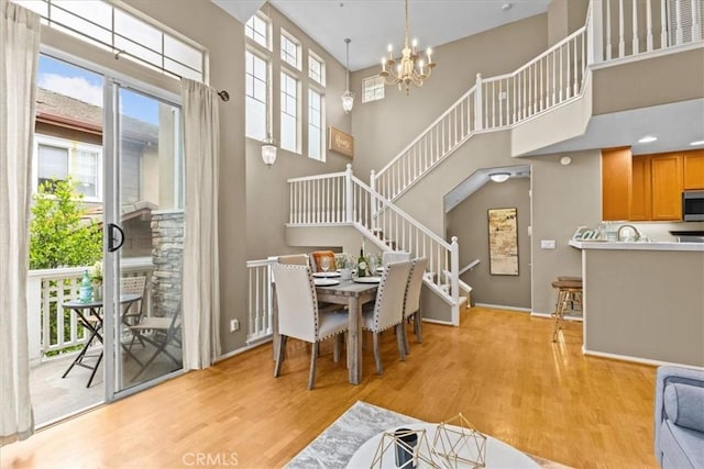 74 Garrison Loop, Ladera Ranch, CA 92694 - dining room featuring light wood-type flooring, a towering ceiling, stairway, and a chandelier