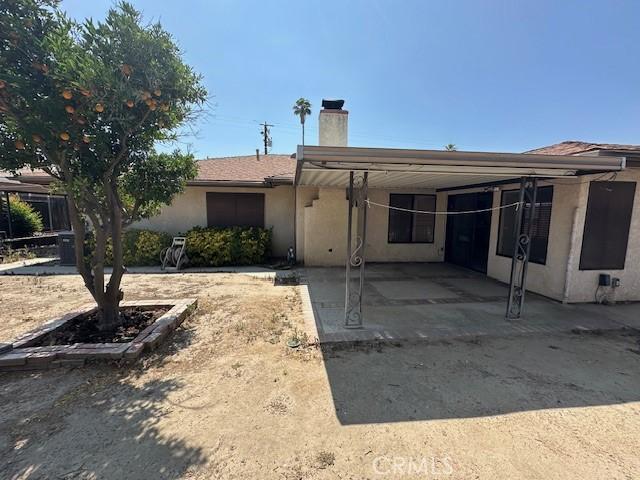 27208 Cornell St, Hemet, CA 92544 - rear view of house featuring a chimney, stucco siding, and a carport