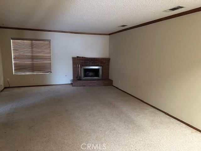 27208 Cornell St, Hemet, CA 92544 - unfurnished living room with ornamental molding, carpet floors, a fireplace, and a textured ceiling