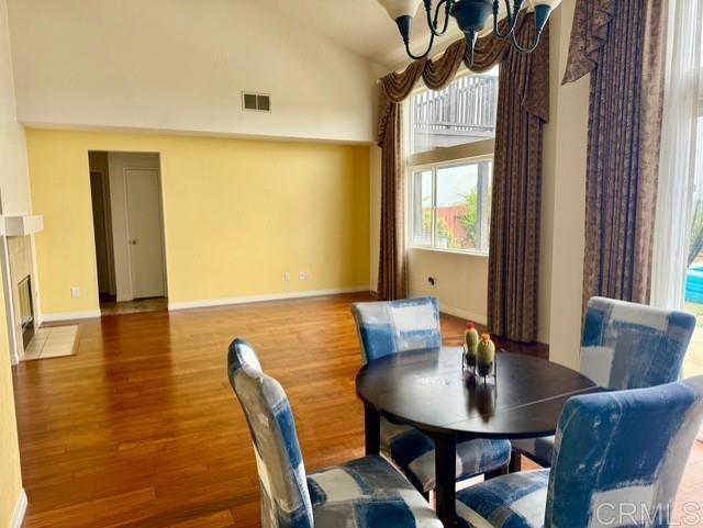 4722 Regatta Ln, San Diego, CA 92154 - dining area featuring a chandelier, wood finished floors, lofted ceiling, and a fireplace with flush hearth