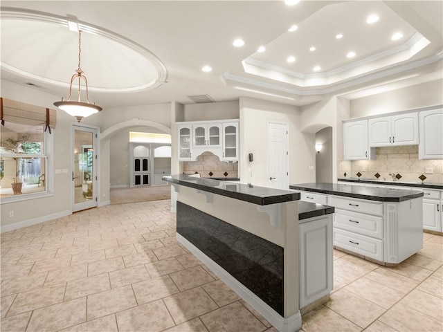 6660 N St Catherine Ct, Fresno, CA 93711 - kitchen with arched walkways, a center island, dark countertops, ornamental molding, and a raised ceiling
