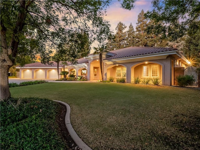 6660 N St Catherine Ct, Fresno, CA 93711 - mediterranean / spanish home with a tiled roof, a front lawn, stucco siding, curved driveway, and an attached garage