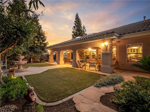 6660 N St Catherine Ct, Fresno, CA 93711 - back of house at dusk featuring a patio area, a tile roof, and stucco siding