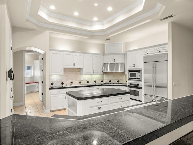 6660 N St Catherine Ct, Fresno, CA 93711 - kitchen featuring built in appliances, under cabinet range hood, arched walkways, ornamental molding, and a raised ceiling