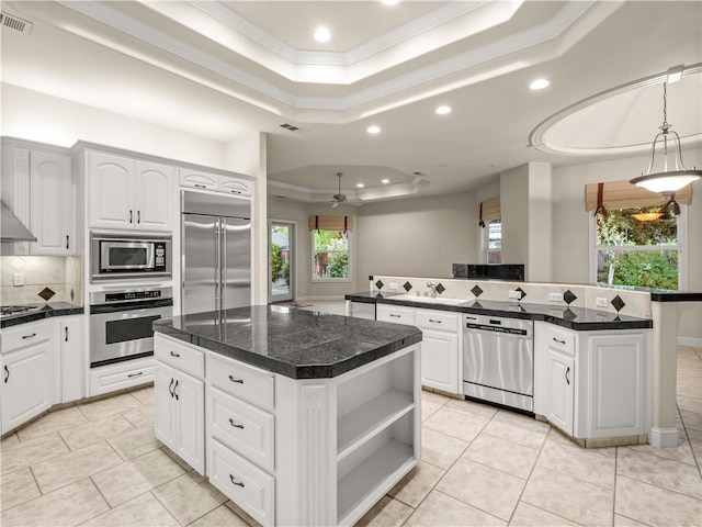 6660 N St Catherine Ct, Fresno, CA 93711 - kitchen featuring built in appliances, a tray ceiling, a kitchen island, recessed lighting, and ornamental molding
