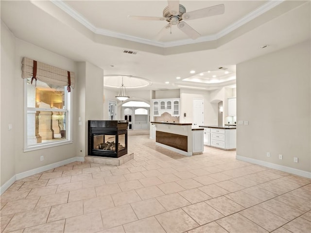 6660 N St Catherine Ct, Fresno, CA 93711 - unfurnished living room featuring a raised ceiling, ceiling fan, plenty of natural light, arched walkways, and crown molding