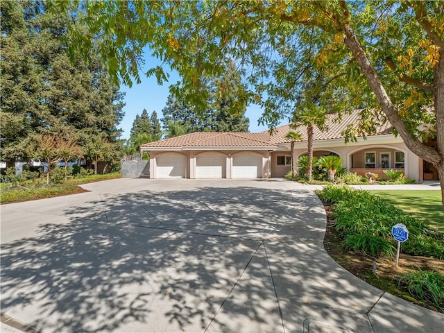 6660 N St Catherine Ct, Fresno, CA 93711 - mediterranean / spanish-style house with driveway, stucco siding, a garage, and a tile roof