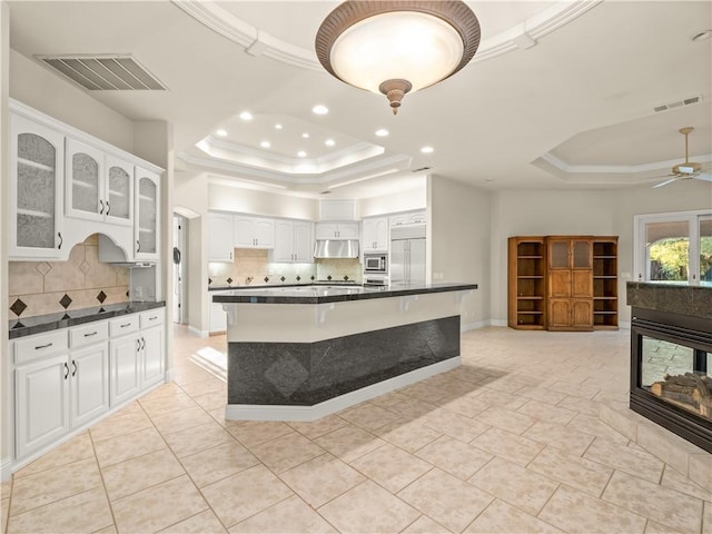 6660 N St Catherine Ct, Fresno, CA 93711 - kitchen featuring a raised ceiling, dark countertops, built in appliances, tasteful backsplash, and crown molding