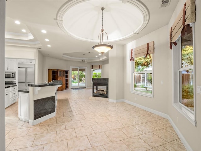 6660 N St Catherine Ct, Fresno, CA 93711 - kitchen with a raised ceiling, built in appliances, open floor plan, a breakfast bar, and dark countertops