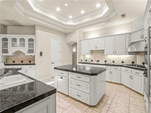 6660 N St Catherine Ct, Fresno, CA 93711 - kitchen with a kitchen island, arched walkways, a raised ceiling, dark countertops, and ornamental molding