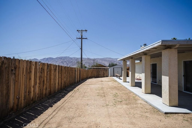 6025 Abronia Ave Unit 29, Palms, CA 92277 - fenced backyard featuring a storage unit, a mountain view, and a patio area