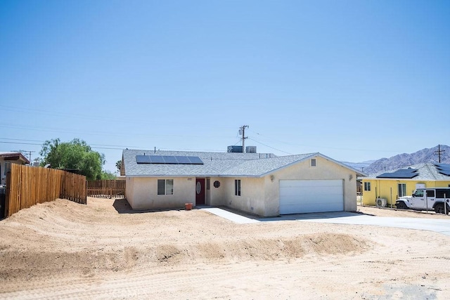 6025 Abronia Ave Unit 29, Palms, CA 92277 - single story home with an attached garage, concrete driveway, roof mounted solar panels, a mountain view, and stucco siding
