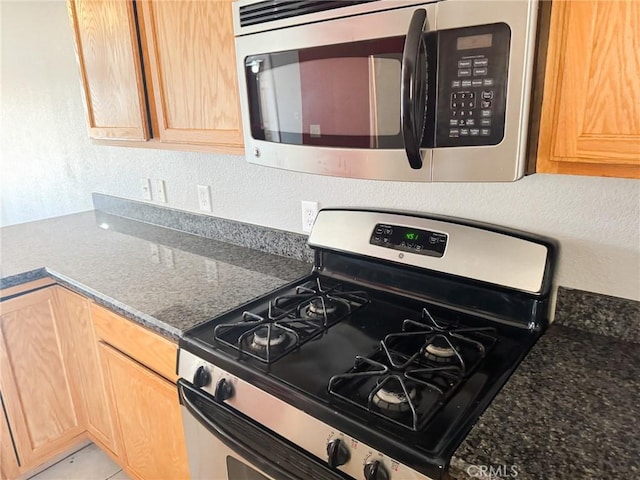 6025 Abronia Ave Unit 29, Palms, CA 92277 - kitchen featuring stainless steel appliances, light brown cabinets, a textured wall, and dark stone counters