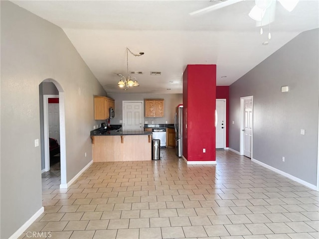 6025 Abronia Ave Unit 29, Palms, CA 92277 - kitchen with a peninsula, stainless steel appliances, open floor plan, arched walkways, and vaulted ceiling