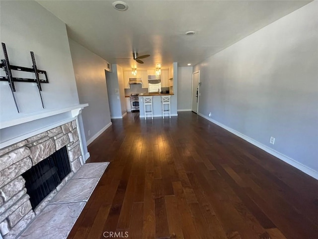 3641 S Bear St Unit F, Santa Ana, CA 92704 - unfurnished living room featuring a stone fireplace, dark wood-type flooring, and a ceiling fan