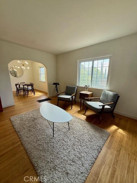 4544 Tulip Ave, Oakland, CA 94619 - living room featuring healthy amount of natural light, wood finished floors, arched walkways, and a chandelier