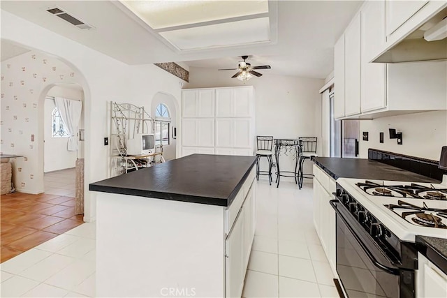 6333 Carodean Rd Unit 29, Palms, CA 92277 - kitchen featuring range with gas cooktop, dark countertops, under cabinet range hood, arched walkways, and a ceiling fan