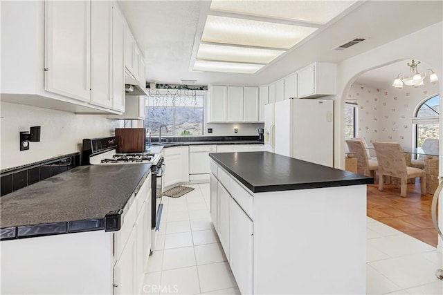 6333 Carodean Rd Unit 29, Palms, CA 92277 - kitchen with white appliances, dark countertops, light tile patterned floors, arched walkways, and plenty of natural light