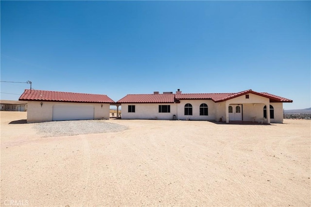 6333 Carodean Rd Unit 29, Palms, CA 92277 - view of front of house featuring stucco siding, a garage, gravel driveway, an outbuilding, and a chimney