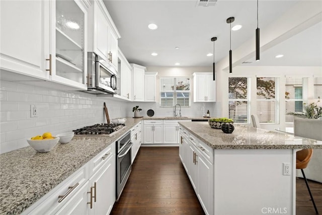 135 Acamar, Irvine, CA 92618 - kitchen featuring stainless steel appliances, glass insert cabinets, a kitchen bar, white cabinetry, and tasteful backsplash