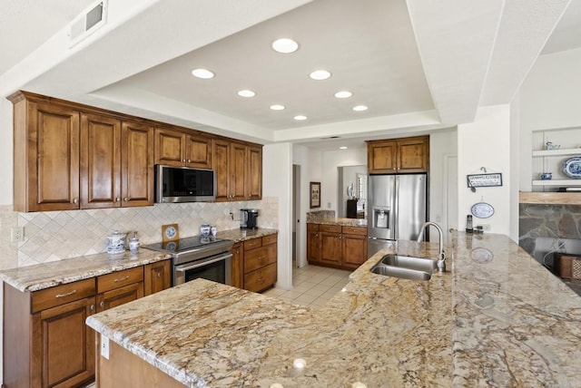 2221 Cortina Cir, Escondido, CA 92029 - kitchen featuring stainless steel appliances, a raised ceiling, decorative backsplash, light stone counters, and brown cabinets