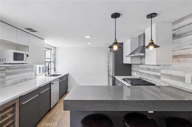 434 S Los Robles Ave Unit 4, Pasadena, CA 91101 - kitchen featuring wall chimney range hood, appliances with stainless steel finishes, beverage cooler, decorative backsplash, and light wood finished floors