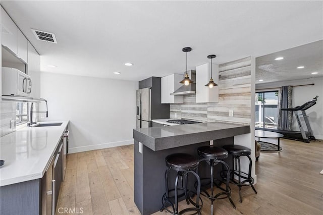 434 S Los Robles Ave Unit 4, Pasadena, CA 91101 - kitchen with wall chimney range hood, light wood-style flooring, a kitchen bar, backsplash, and white cabinetry