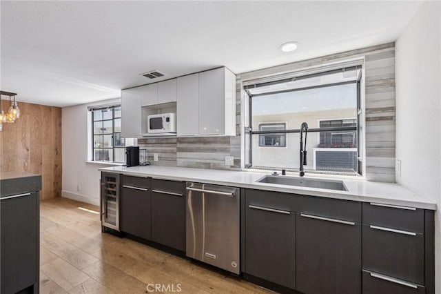 434 S Los Robles Ave Unit 4, Pasadena, CA 91101 - kitchen featuring stainless steel dishwasher, beverage cooler, white microwave, light countertops, and white cabinetry