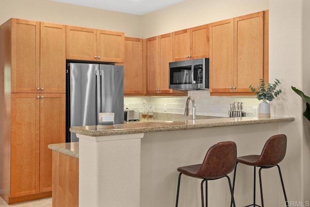 12737 Savannah Creek Dr Unit 280, San Diego, CA 92128 - kitchen with appliances with stainless steel finishes, a breakfast bar, tasteful backsplash, light stone counters, and a peninsula