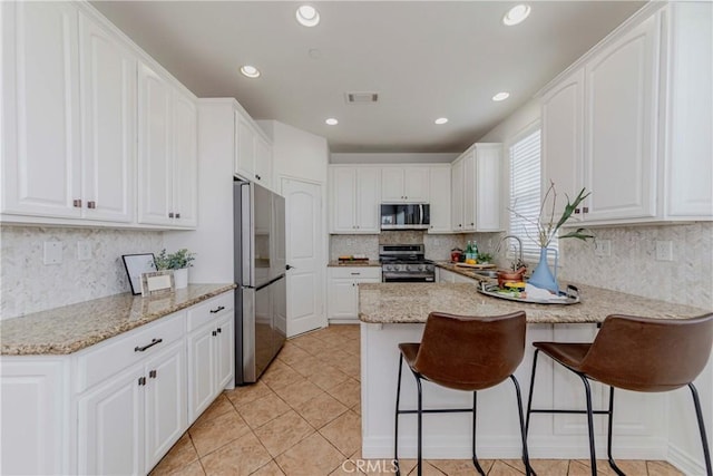 8647 Belmont St, Cypress, CA 90630 - kitchen with appliances with stainless steel finishes, a peninsula, white cabinets, a breakfast bar area, and recessed lighting