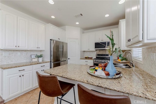 8647 Belmont St, Cypress, CA 90630 - kitchen featuring appliances with stainless steel finishes, a peninsula, a kitchen bar, white cabinetry, and recessed lighting