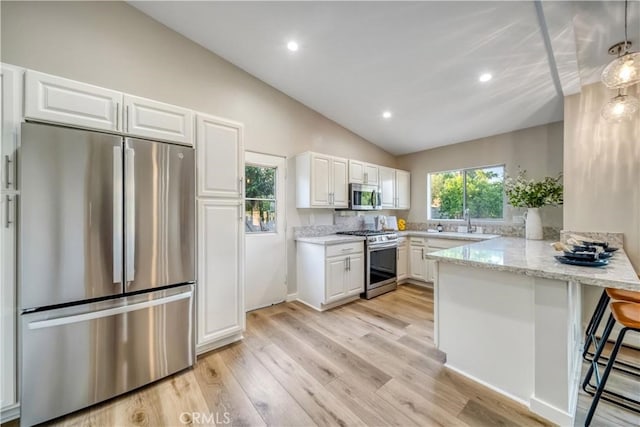 73466 Salt, Cedar, Palm Desert, CA 92260 - kitchen with stainless steel appliances, a peninsula, lofted ceiling, white cabinets, and a kitchen bar