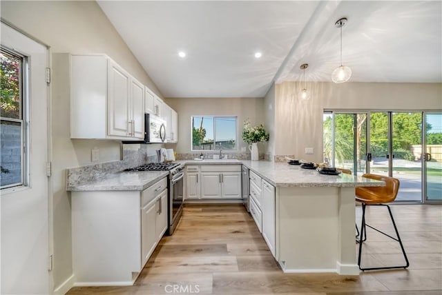 73466 Salt, Cedar, Palm Desert, CA 92260 - kitchen featuring stainless steel appliances, a peninsula, white cabinets, a kitchen bar, and light stone counters
