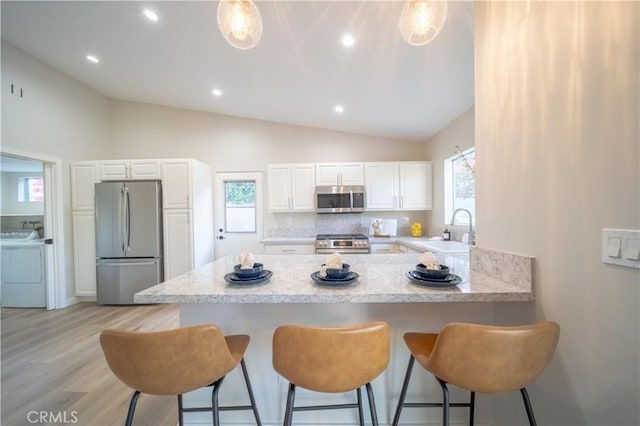 73466 Salt, Cedar, Palm Desert, CA 92260 - kitchen featuring appliances with stainless steel finishes, lofted ceiling, a peninsula, white cabinetry, and a breakfast bar