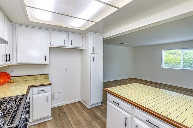 15015 Tacuba Dr, La Mirada, CA 90638 - kitchen with wood finished floors, stainless steel range with gas stovetop, white cabinetry, and tile counters