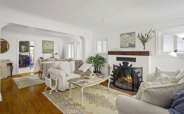 4260 Mcconnell Blvd, Los Angeles, CA 90066 - living room featuring arched walkways, wood finished floors, and a warm lit fireplace